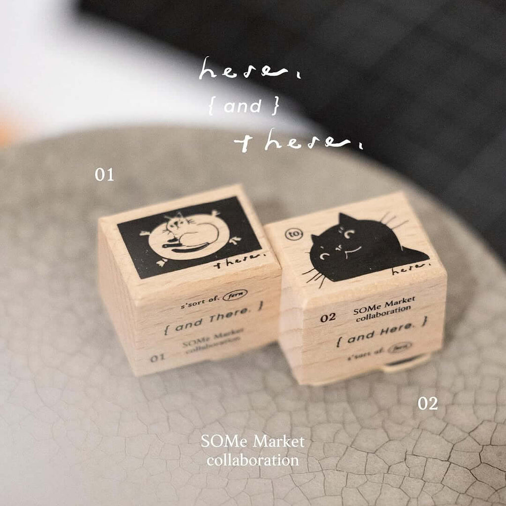 Two wooden blocks with cat illustrations on a gray surface and brown background.