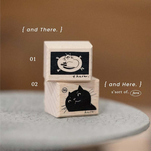Two wooden blocks with cat illustrations on a gray surface and brown background.