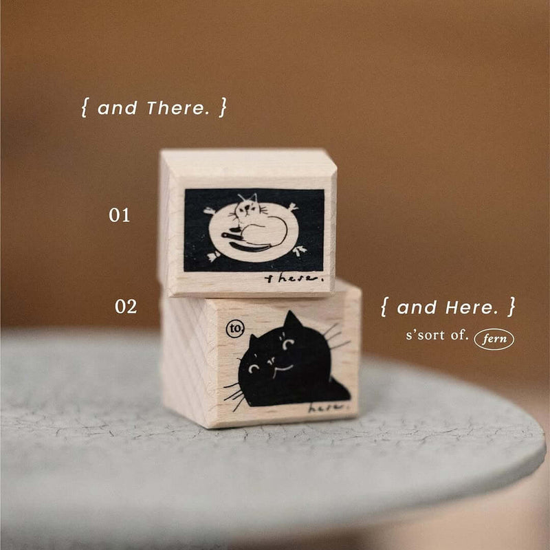Two wooden blocks with cat illustrations on a gray surface and brown background.